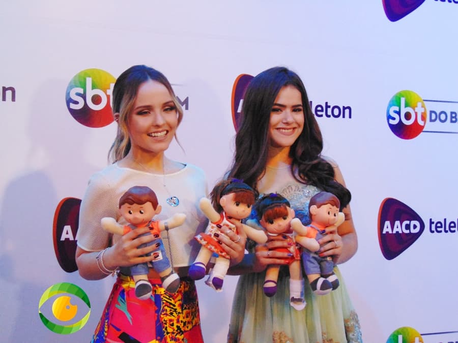 Duas jovens garotas estão sorridentes e seguram bonecos nas mãos Duas jovens garotas estão sorridentes e seguram bonecos nas mãos