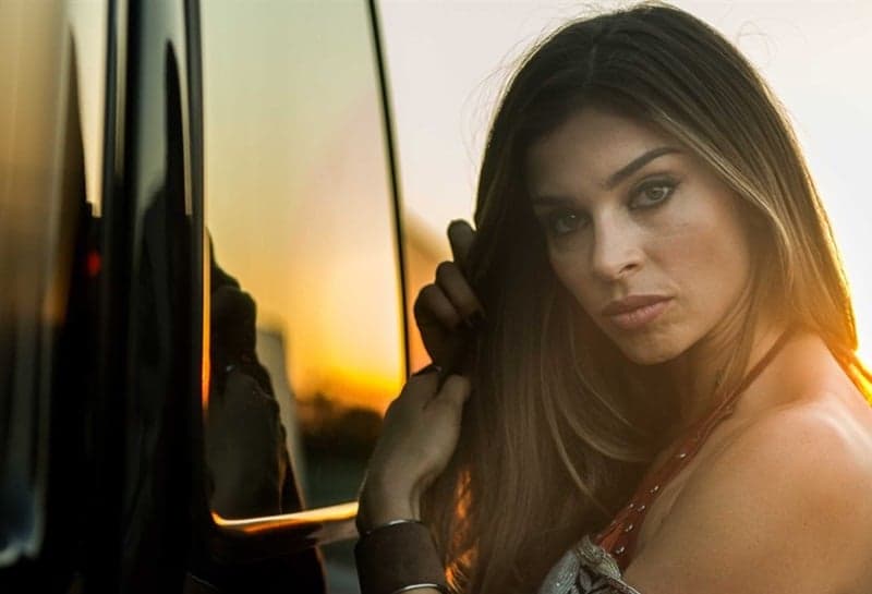 mulher séria posando para fotógrafo segurando o seu cabelo e seu reflexo em o carro, atriz de "O Outro Lado do Paraíso"