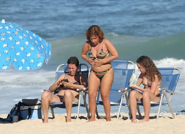 Claudia Rodrigues é flagrada na praia do Rio de Janeiro com a filha e a empresária