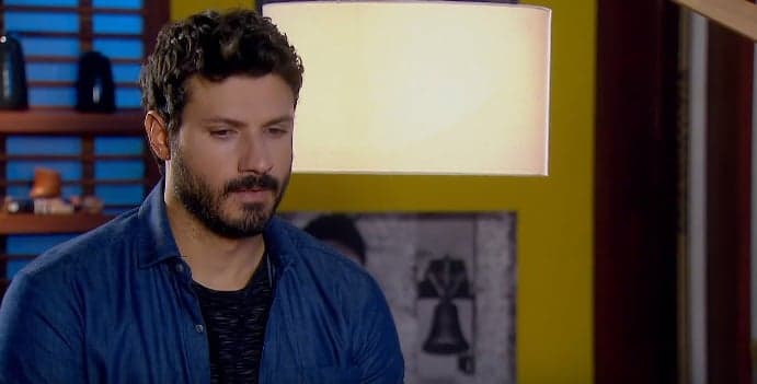 Personagem de As Aventuras de Poliana, Marcelo em cena de cabeça abaixada, ele usa camisa social azul e barba Personagem de As Aventuras de Poliana, Marcelo em cena de cabeça abaixada, ele usa camisa social azul e barba