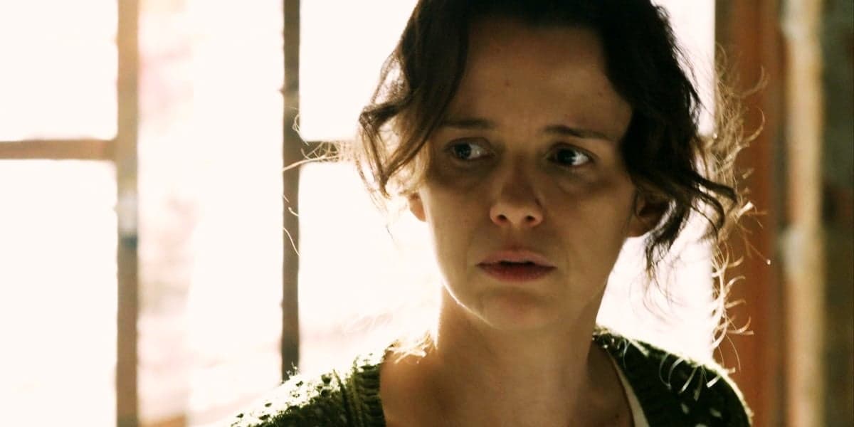 Lorraine usando casaco verde de trico, em contra luz da janela em cena de Império Lorraine usando casaco verde de trico, em contra luz da janela em cena de Império
