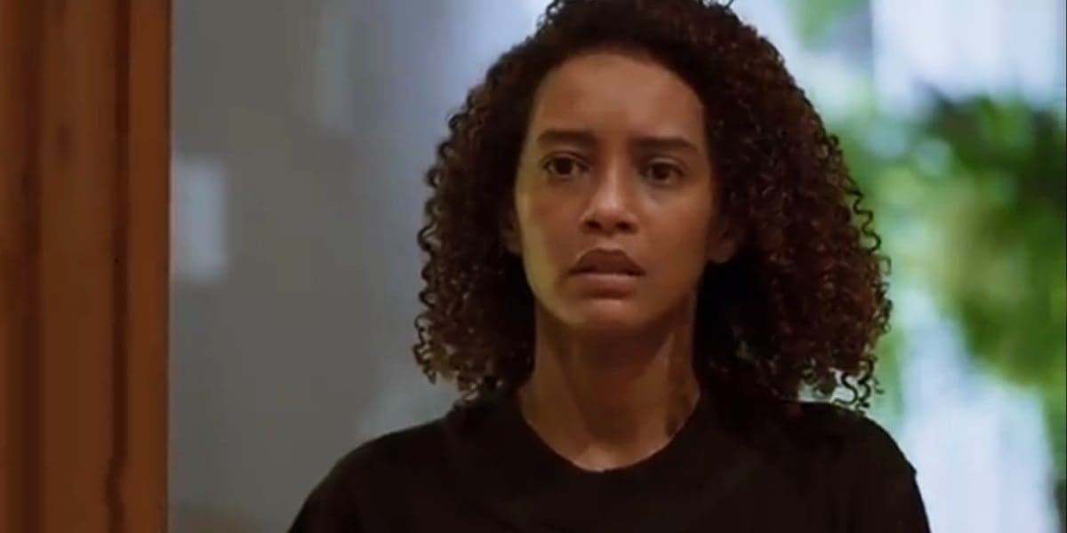 Vitória usando camiseta preta, mulher negra com cabeços cacheados em cena de Amor de Mãe Vitória usando camiseta preta, mulher negra com cabeços cacheados em cena de Amor de Mãe