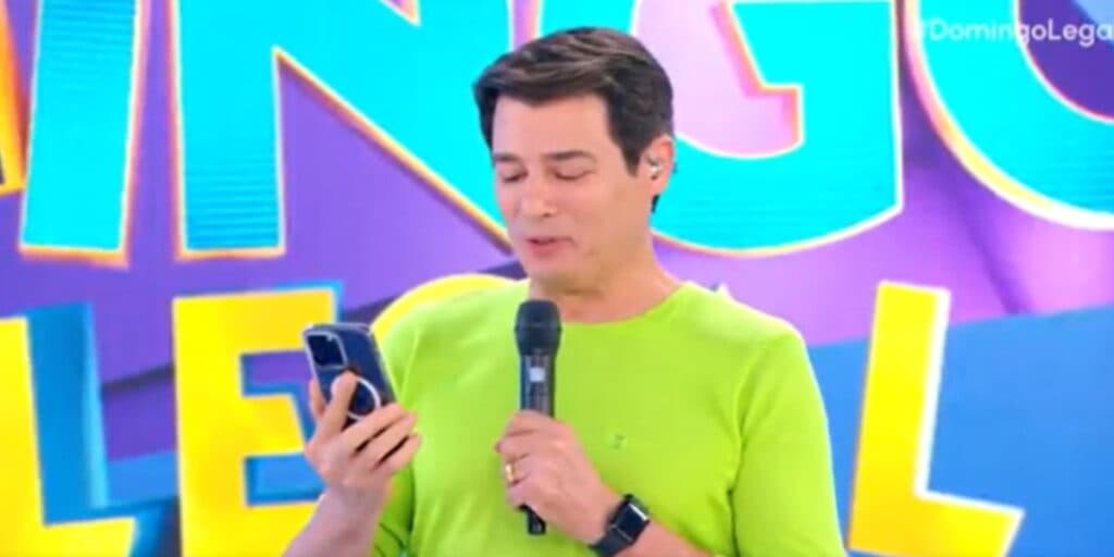 Celso Portiolli para Domingo Legal no SBT, olha celular e dá notícia bombástica sobre filha de Silvio Santos