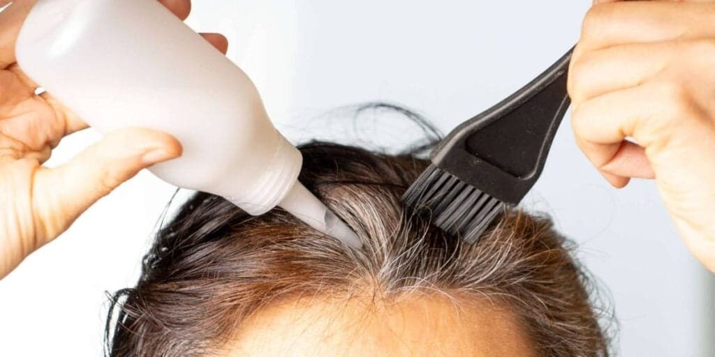 Mulher aplicando tinta no cabelo (Foto: Reprodução / Internet) 