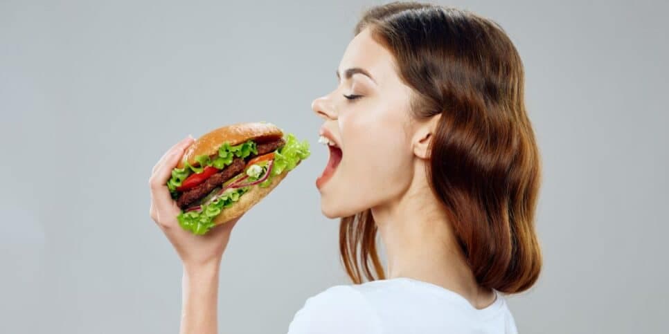 Mulher comendo lanche (Foto: Canva)