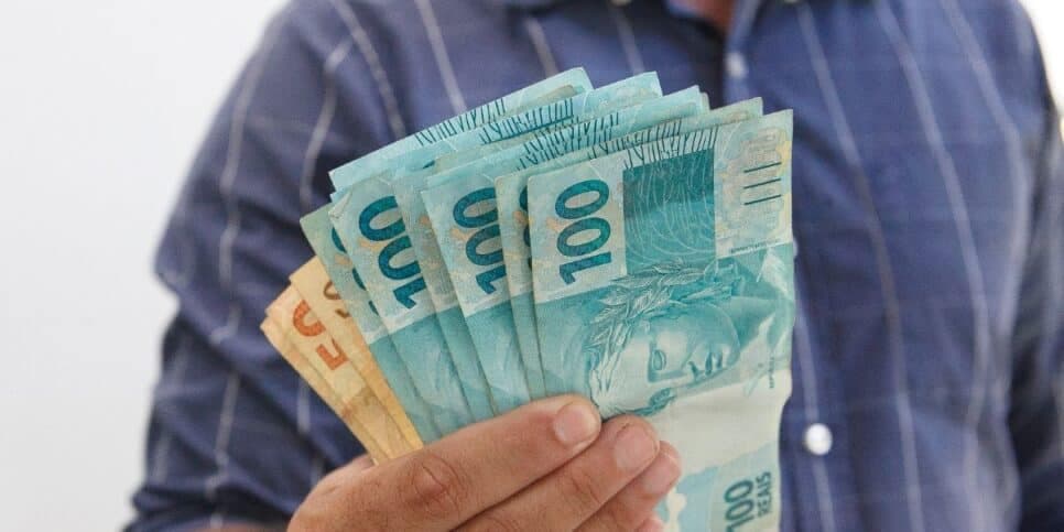 Homem segurando notas de real (Foto: Canva)