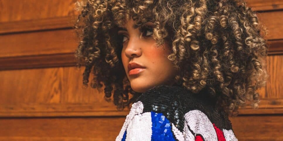 Jovem com o cabelo cacheado (Foto: Canva)