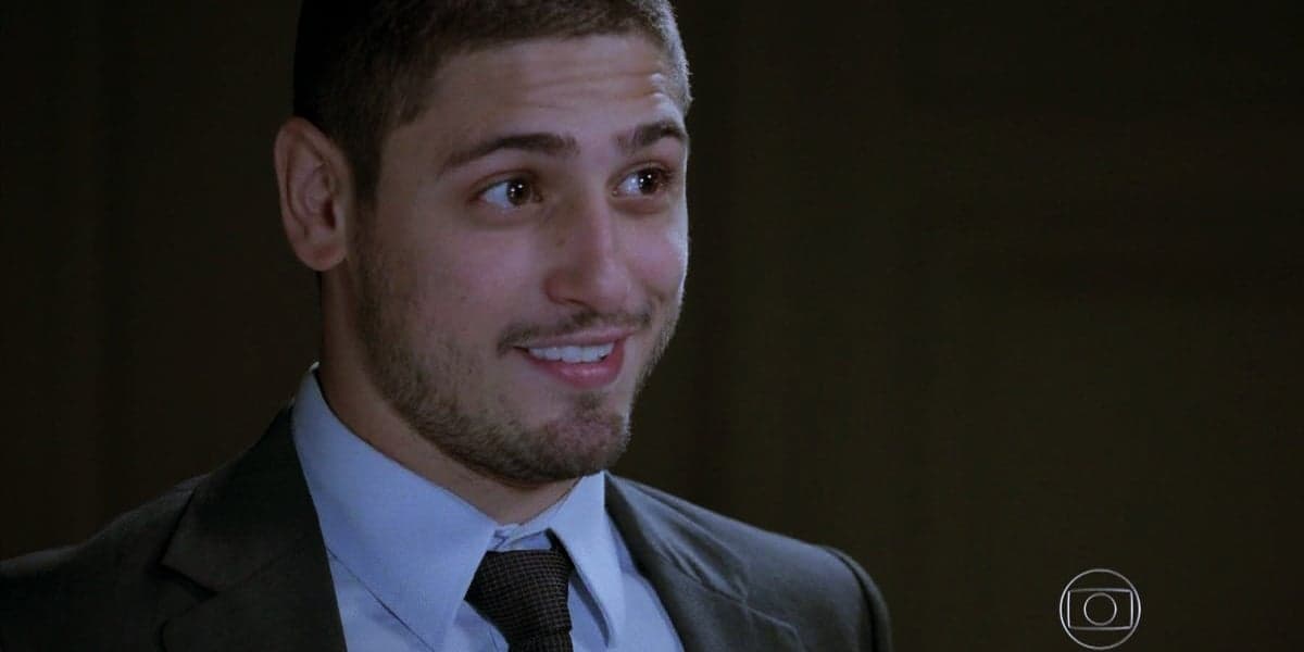 João Lucas em cena da novela Império usando terno cinza, camisa social azul e gravata preta João Lucas em cena da novela Império usando terno cinza, camisa social azul e gravata preta