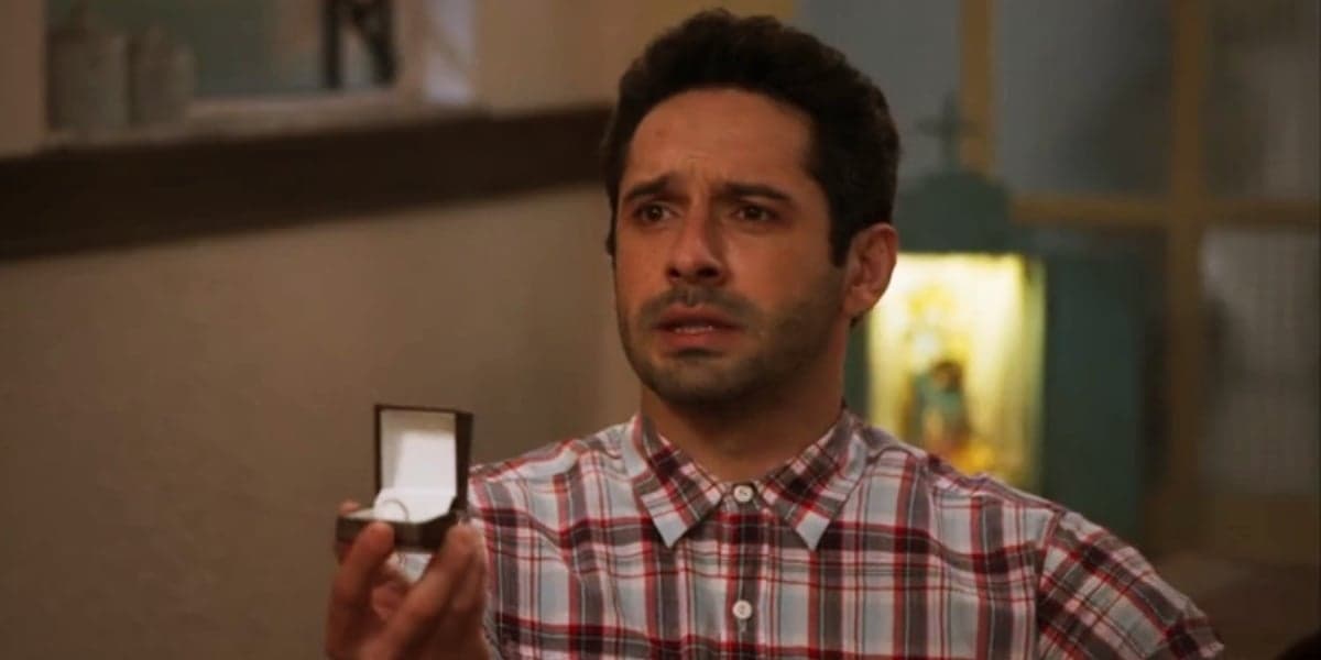 Zezinho usa camisa xadrez e segura uma caixinha com anel nas mãos em cena de Salve-se Quem Puder Zezinho usa camisa xadrez e segura uma caixinha com anel nas mãos em cena de Salve-se Quem Puder