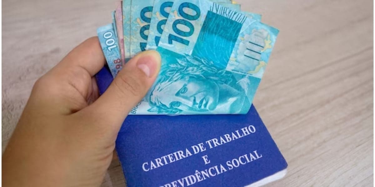 Carteira de trabalho e notas de dinheiro na mão de trabalhador - Foto Reprodução Internet Carteira de trabalho e notas de dinheiro na mão de trabalhador - Foto Reprodução Internet