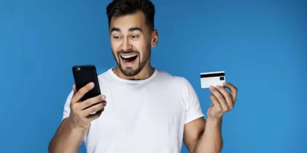 Homem segurando celular e cartão de crédito (Foto: Reprodução / Freepik) Homem segurando celular e cartão de crédito (Foto: Reprodução / Freepik)